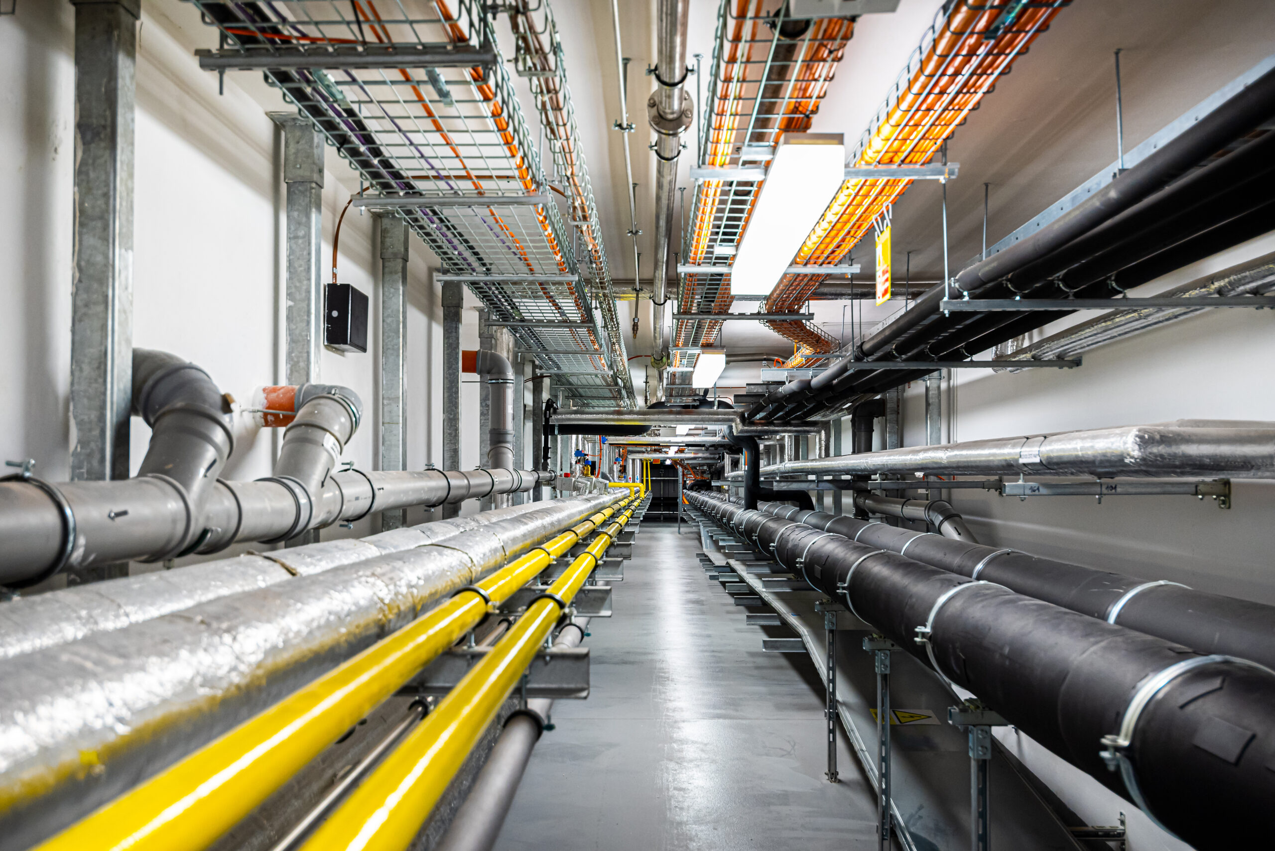 Gas and waste pipelines in the underground premises of the factory, industrial background, building utilities